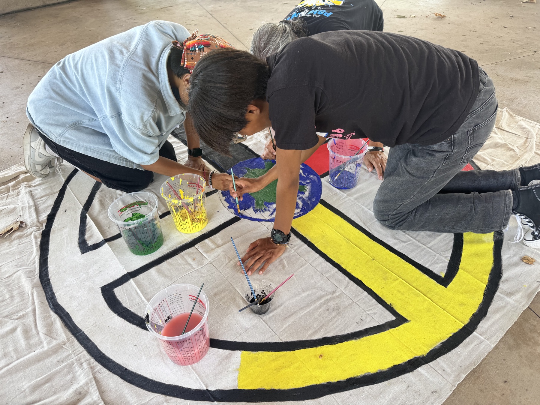 Young people painting a colorful Medicine Wheel mural together.